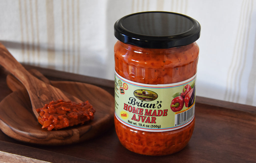 Jar of 'Brian's Homemade Ajvar' with a wooden spoon on a wooden surface
