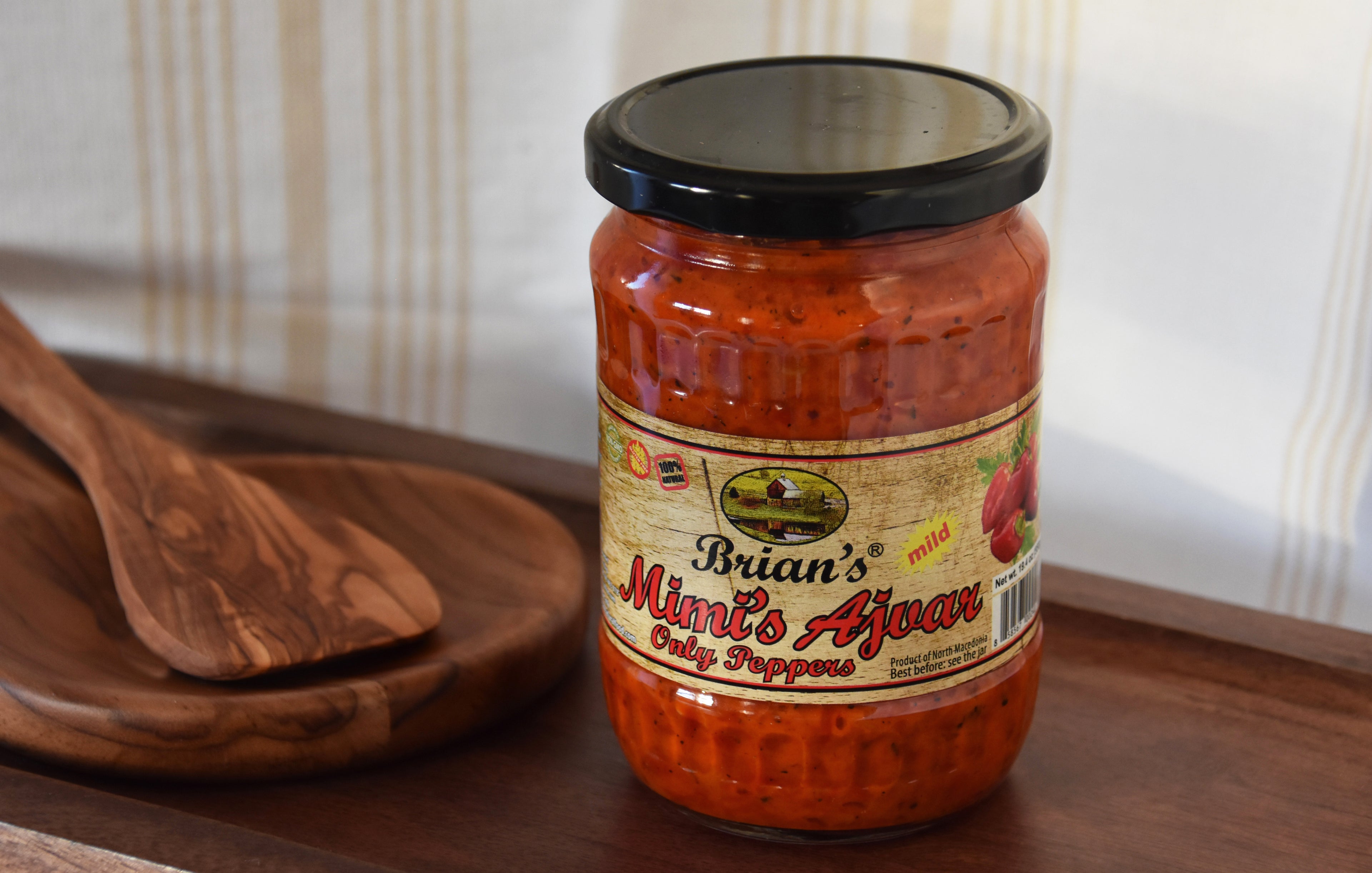 Jar of 'Brian's Mimi's Ajoar' on a wooden surface with a wooden spoon in the background.